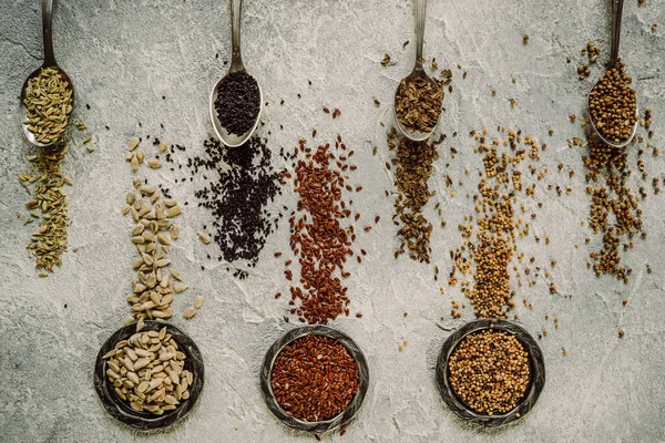 stock image fresh natural cleaned sunflower seeds, flax and aromatic spices on gray concrete background