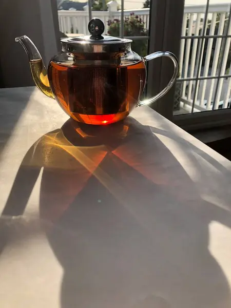 stock image Glass teapot and sunlight at the table against the window