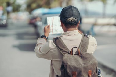 Turistler eğlence, restoran ya da otel bulmak için haritalar tutuyorlar. Sırt çantası ve seyahat kavramı.