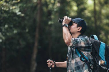 Yürüyüşçüler hayvanları görmek için dürbün kullanır ve ormanda sırt çantalı manzarayı görürler. yürüyüş ve macera konsepti.