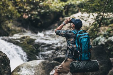 Yürüyüşçüler hayvanları görmek için dürbün kullanır ve ormanda sırt çantalı manzarayı görürler. yürüyüş ve macera konsepti.