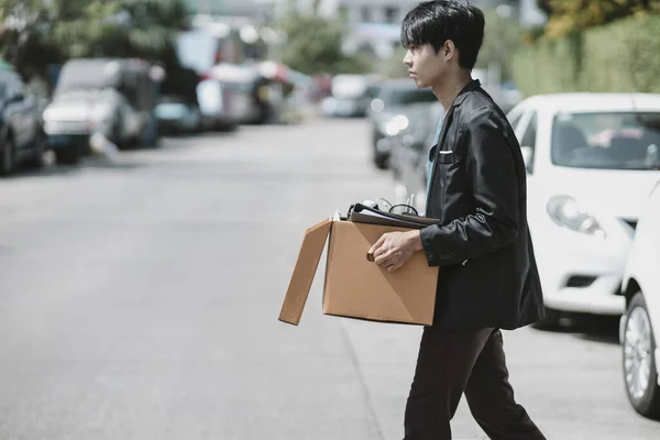 Businessman fired or resign from the company are carrying boxes down the street looking for a new job. Unemployed, hiring job, quitting job concept