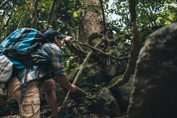 stock image Hikers are rock climbing using their hands on the vines to climb to the top. hiking and adventure concept.