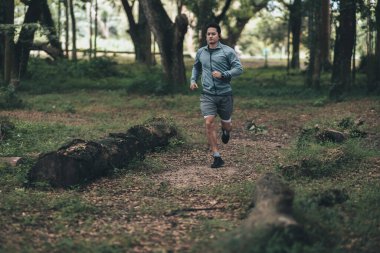 Ormanı yöneten sağlıklı yaşam tarzı genç bir fitness adamı. Açık hava sporu, sağlıklı yaşam tarzı konsepti.