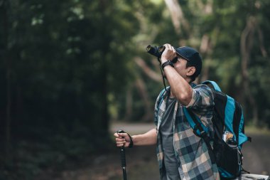 Yürüyüşçüler hayvanları görmek için dürbün kullanır ve ormanda sırt çantalı manzarayı görürler. yürüyüş ve macera konsepti.
