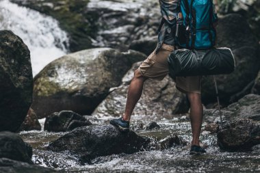 Yürüyüşçüler sırt çantalı yürüyüş direğini ormanda akarsuda ve kayalarda yürürken kullanırlar. yürüyüş ve macera konsepti.