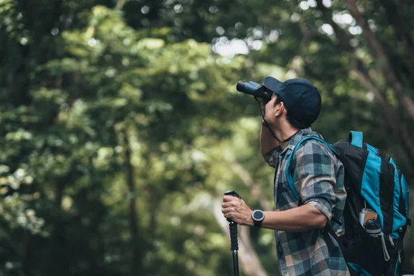 stock image Hikers use binocular to see animals and view landscape  with backpacks walking through on the road in the forest. hiking and adventure concept.