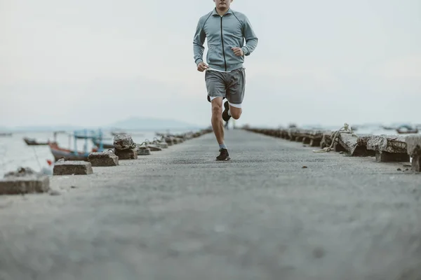 健康的生活方式年轻健康的男人在海边的一座古老的桥上跑步 户外运动 健康生活方式概念 — 图库照片