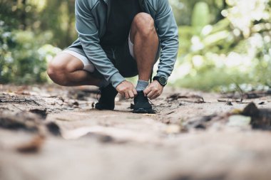 Spor adamı ormanda koşu ayakkabısı bağlıyor. Açık hava sporu, sağlıklı yaşam tarzı konsepti.