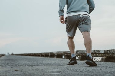 Sahil kenarındaki eski köprüde koşan sağlıklı yaşam tarzı genç bir fitness adamı. Açık hava sporu, sağlıklı yaşam tarzı konsepti.