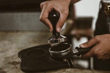 Barista, portafilter 'a kahve basmak için kurcalayıcı kullanıyor. Kahve makinesi konsepti