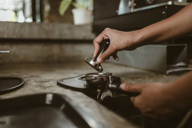 Barista, portafilter 'a kahve basmak için kurcalayıcı kullanıyor. Kahve makinesi konsepti