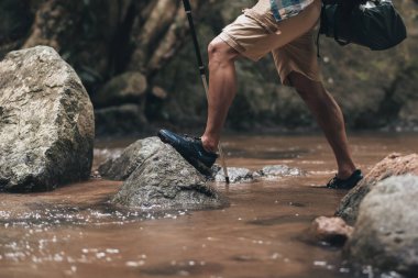 Yürüyüşçüler sırt çantalı yürüyüş direğini ormanda akarsuda ve kayalarda yürürken kullanırlar. yürüyüş ve macera konsepti.