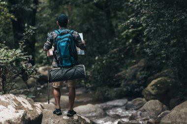 Yürüyüşçüler ormanda kayaların üzerinde duran sırt çantalı yürüyüş direğini kullanırlar. yürüyüş ve macera konsepti.