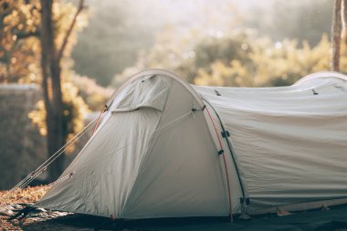 Ormandaki çimlerin üzerindeki gri çadır Arkadaki manzara sabahları dağdır. Kamp, seyahat ve tatil konsepti.