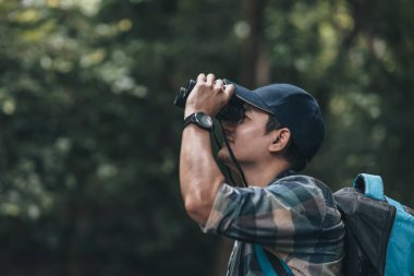 Yürüyüşçüler hayvanları görmek için dürbün kullanır ve ormanda sırt çantalı manzarayı görürler. yürüyüş ve macera konsepti.