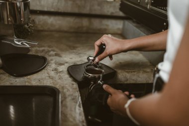 Barista, portafilter 'a kahve basmak için kurcalayıcı kullanıyor. Kahve makinesi konsepti