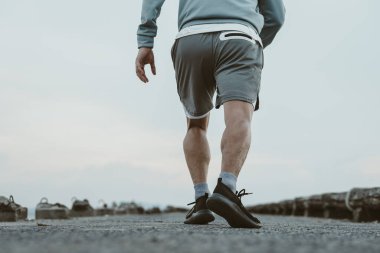 Sahil kenarındaki eski köprüde koşan sağlıklı yaşam tarzı genç bir fitness adamı. Açık hava sporu, sağlıklı yaşam tarzı konsepti.