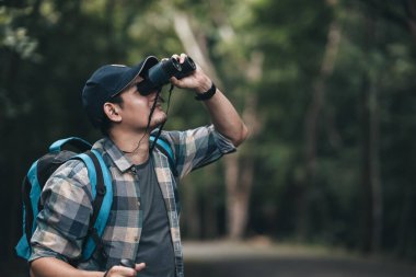 Yürüyüşçüler hayvanları görmek için dürbün kullanır ve ormanda sırt çantalı manzarayı görürler. yürüyüş ve macera konsepti.
