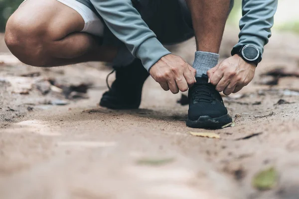 stock image Sport man  tying jogging shoes in the forest. Outdoor workout,  Healthy lifestyle concept.