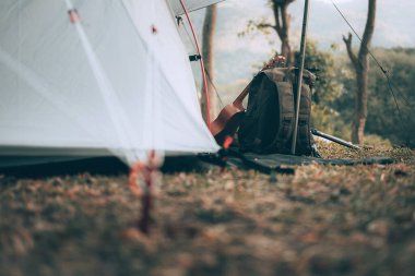 Kamp malzemeleri, çantalar, ayakkabılar, ukulele, sabahları çadırın yanında tripod. Nesne kampı, seyahat ve meslek kavramı.