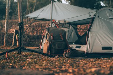 Kamp malzemeleri, çantalar, ayakkabılar, ukulele, sabahları çadırın yanında tripod. Nesne kampı, seyahat ve meslek kavramı.