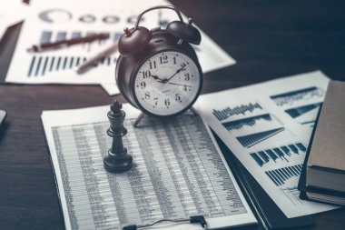 Satranç takımları içindeki krallar ve finansal belgelere yerleştirilmiş çalar saatler işlerinde mükemmelliği göstermek zaman alır. Soyut İş Konsepti.