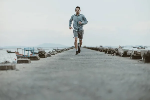 健康的生活方式年轻健康的男人在海边的一座古老的桥上跑步 户外运动 健康生活方式概念 — 图库照片