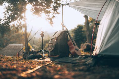 Kamp malzemeleri, çantalar, ayakkabılar, ukulele, sabahları çadırın yanında tripod. Nesne kampı, seyahat ve meslek kavramı.