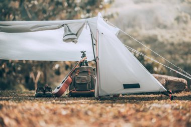 Kamp malzemeleri, çantalar, ayakkabılar, ukulele, sabahları çadırda tripod. Nesne kampı, seyahat ve meslek kavramı.