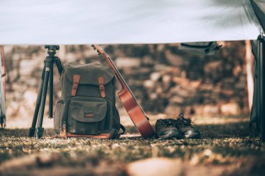Kamp malzemeleri, çantalar, ayakkabılar, ukulele, sabahları çadırda tripod. Nesne kampı, seyahat ve meslek kavramı.