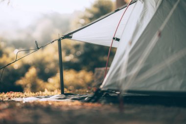 Ormandaki çimlerin üzerindeki gri çadır Arkadaki manzara sabahları dağdır. Kamp, seyahat ve tatil konsepti.