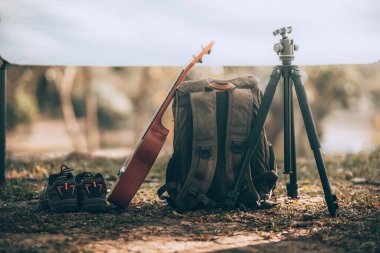 Kamp malzemeleri, çantalar, ayakkabılar, ukulele, sabahları çadırda tripod. Nesne kampı, seyahat ve meslek kavramı.