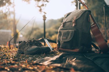 Kamp malzemeleri, çantalar, ayakkabılar, ukulele, sabahları çadırın yanında tripod. Nesne kampı, seyahat ve meslek kavramı.