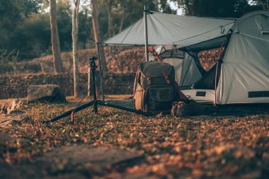 Kamp malzemeleri, çantalar, ayakkabılar, ukulele, sabahları çadırın yanında tripod. Nesne kampı, seyahat ve meslek kavramı.