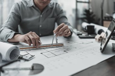 Bölücü pusula kullanarak plan üzerinde çalışan bir mimar. Ev planlama ve inşaat konsepti.