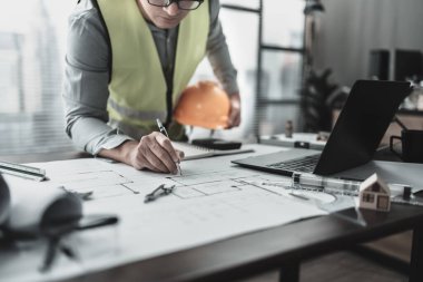Mühendislik güvenlik kaskı ofis masasında çizim teftişiyle çalışıyor. Mühendis, Mimar, Endüstri ve Fabrika Konsepti.