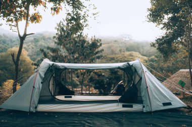 Ormandaki çimlerin üzerindeki gri çadır Arkadaki manzara sabahları dağdır. Kamp, seyahat ve tatil konsepti.