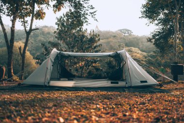 Ormandaki çimlerin üzerindeki gri çadır Arkadaki manzara sabahları dağdır. Kamp, seyahat ve tatil konsepti.