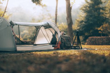 Kamp malzemeleri, çantalar, ayakkabılar, ukulele, sabahları çadırın yanında tripod. Nesne kampı, seyahat ve meslek kavramı.