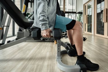 Spor salonunda halterle pazı egzersizi yapan bir adam. Fitness, egzersiz ve trans konsepti.