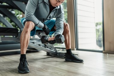 Spor salonunda halterle pazı egzersizi yapan bir adam. Fitness, egzersiz ve trans konsepti.