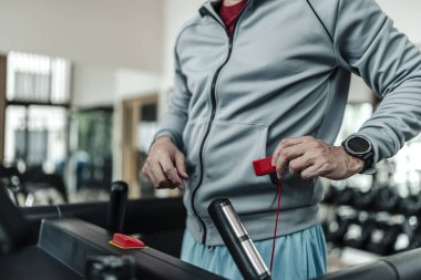 Koşu bandında koşmadan önce acil durum giysilerini bağlayan bir adam, egzersiz fitness. Spor, spor, egzersiz ve yaşam tarzı konsepti.