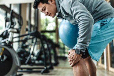 Bir adam spor salonunda pilates topu kullanır ve dizini incitir. Spor, spor, egzersiz ve yaşam tarzı konsepti.