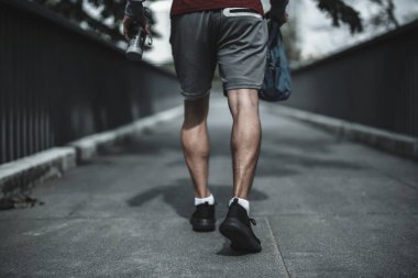 Kardiyo çalışmasından önce şehir merkezindeki parkta yaya köprüsünde yürüyen bir adam. Büyük şehir yaşam konseptinde sağlık ve yaşam tarzı.