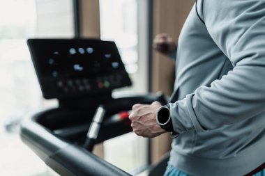Akıllı saat takan, koşu bandında koşan, spor yapan bir adam. Spor, spor, egzersiz ve yaşam tarzı konsepti.