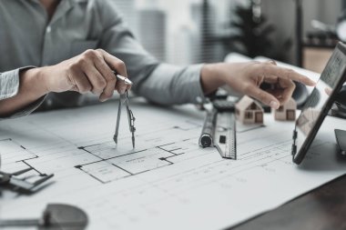 Bölücü pusula kullanarak plan üzerinde çalışan bir mimar. Ev planlama ve inşaat konsepti.