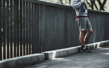 Genç sporcu adam koşudan sonra su içer, parkta koşar. Spor susuzluğu ve egzersizden sonra dinlenme. Büyük şehir yaşam konseptinde sağlık ve yaşam tarzı.