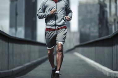 Kardiyo çalışması için şehir merkezindeki parkta yaya köprüsünde koşan bir adam. Büyük şehir yaşam konseptinde sağlık ve yaşam tarzı.