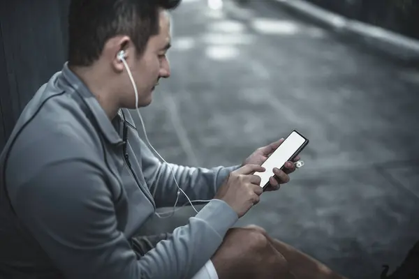 A man use smartphone Fitness application, social media, listening to music.  Health and Lifestyle in big city life concept.